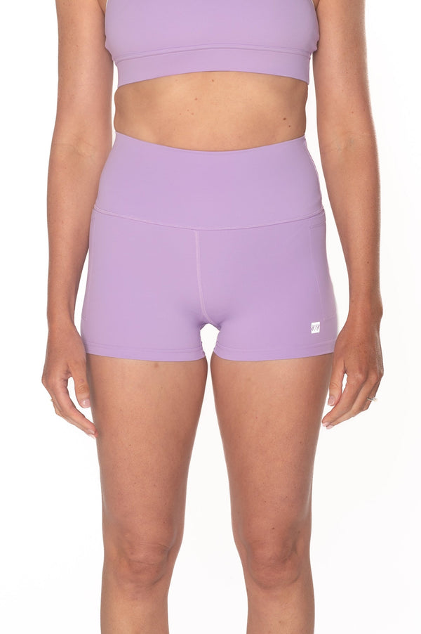 Person wearing a purple sports bra and shorts set on a white background